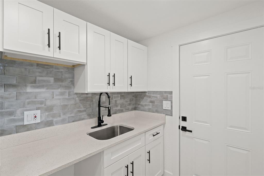 A kitchen features white cabinets, a gray subway tile backsplash, and a stainless steel sink — 2008 OAKWOOD AVENUE UNIT B, TAMPA, FL