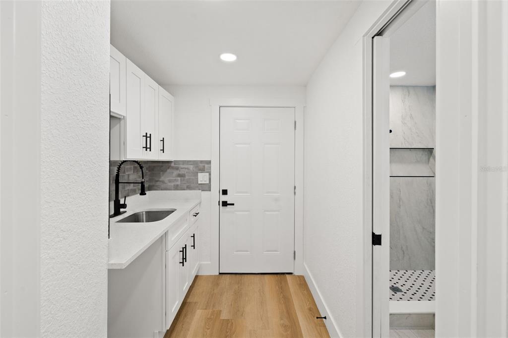 A small kitchenette with white cabinets, a sink, and a door leading to a bathroom — 2008 OAKWOOD AVENUE UNIT B, TAMPA, FL