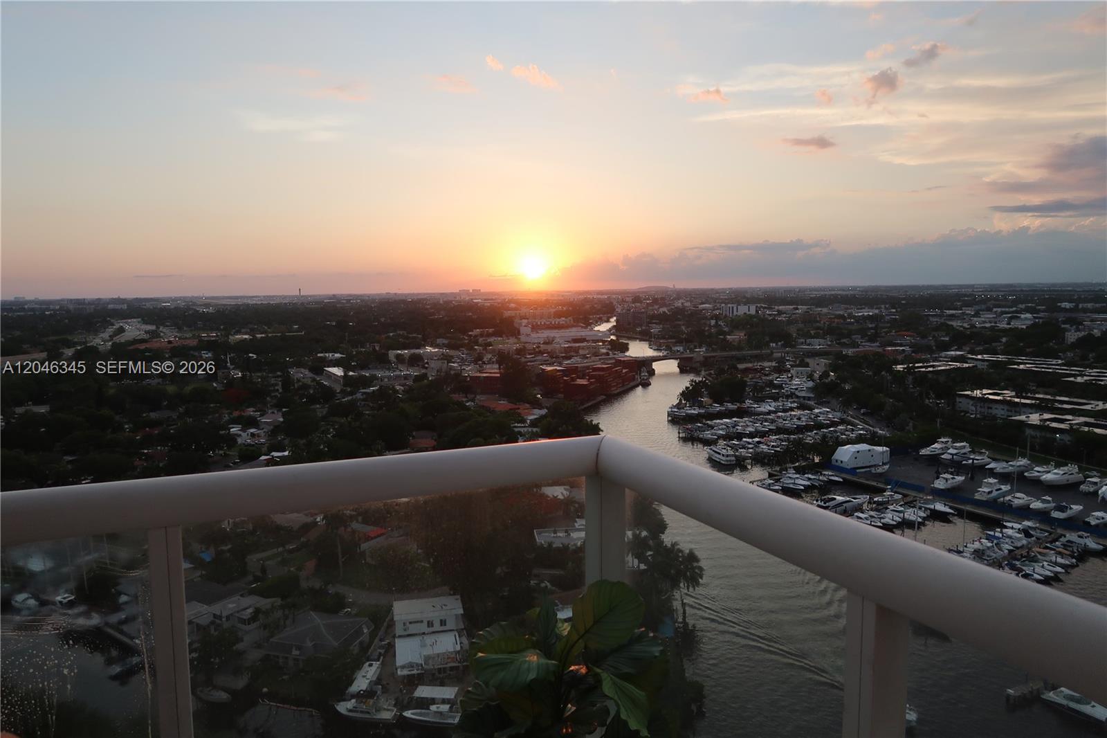 An elevated view from a balcony overlooks a river, a marina, and a sunset — 1861 NW S River Dr # 1505, Miami FL 33125, MIAMI, FL