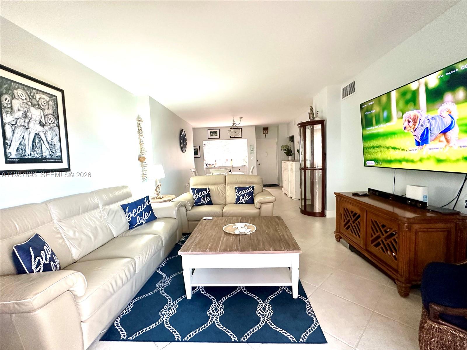 A living room features a beige leather sofa, a wooden coffee table, and a television — 1950 S Ocean Dr # 2C, Hallandale Beach FL 33009, HALLANDALE BEACH, FL