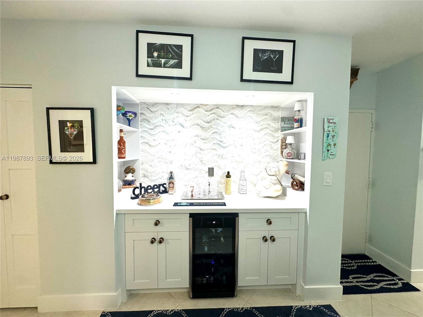 A built-in wet bar features white cabinetry, a wine cooler, and a wavy tile backsplash — 1950 S Ocean Dr # 2C, Hallandale Beach FL 33009, HALLANDALE BEACH, FL