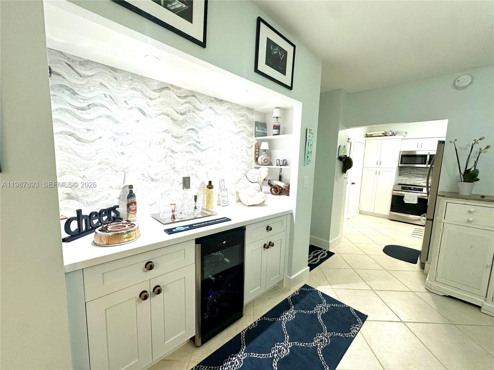 A wet bar with a wavy tile backsplash and white cabinetry sits beside a kitchen — 1950 S Ocean Dr # 2C, Hallandale Beach FL 33009, HALLANDALE BEACH, FL