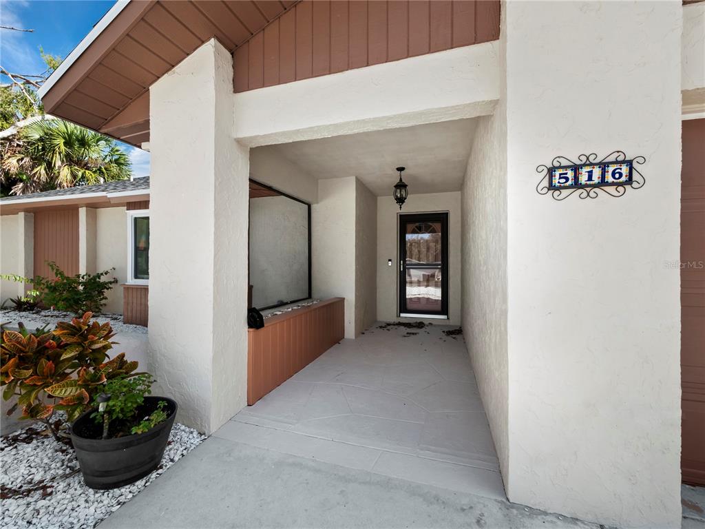 A covered entryway features a front door, a decorative house number sign, and a planter — 516 CASAS BONITAS WAY, NOKOMIS, FL