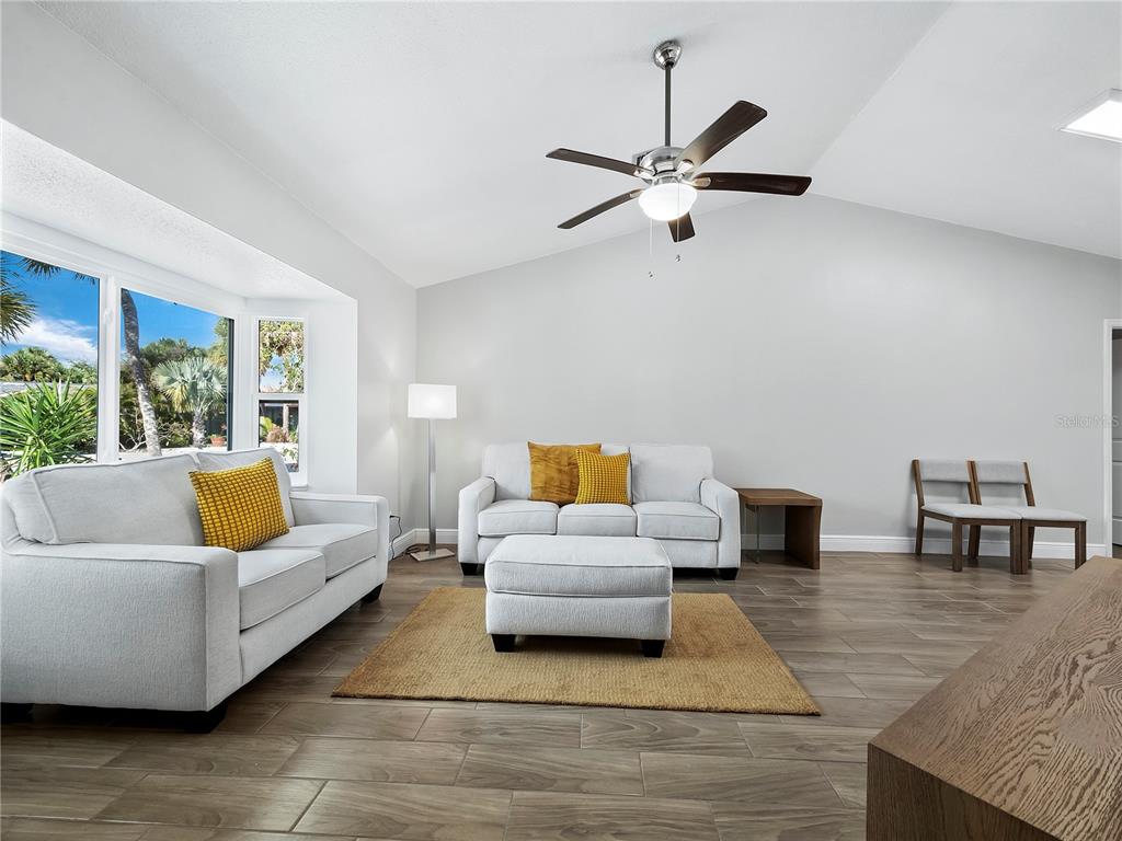 A living room with light gray walls, white sofas, a ceiling fan, and wood-look tile flooring — 516 CASAS BONITAS WAY, NOKOMIS, FL