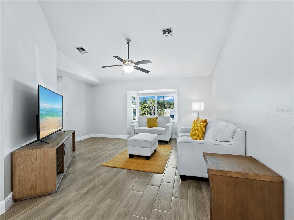 A living room features light wood-look tile floors, a ceiling fan, and white furniture — 516 CASAS BONITAS WAY, NOKOMIS, FL