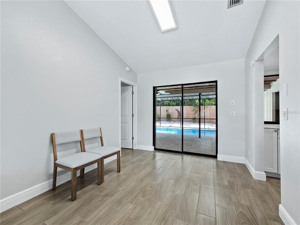 A dining area with wood-look tile flooring, two chairs, and a sliding door to a pool — 516 CASAS BONITAS WAY, NOKOMIS, FL