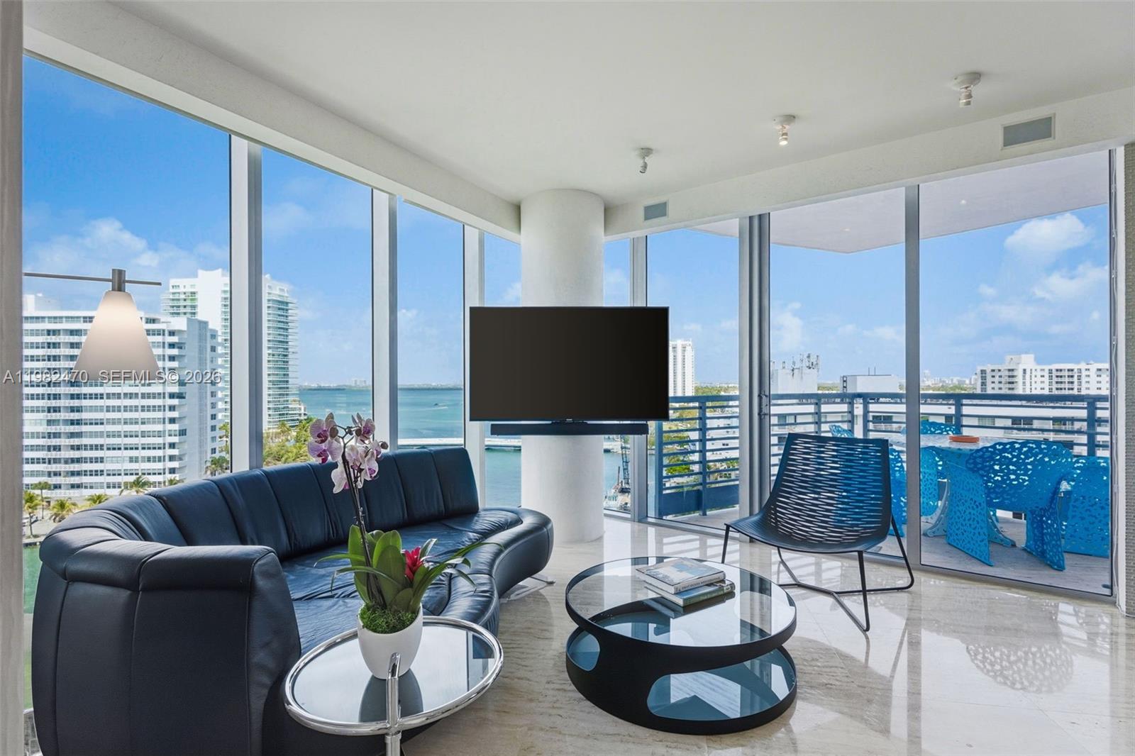 A modern living room features a curved sofa, glass coffee table, and floor-to-ceiling windows — 1445 16th St # 1101, Miami Beach FL 33139, MIAMI BEACH, FL