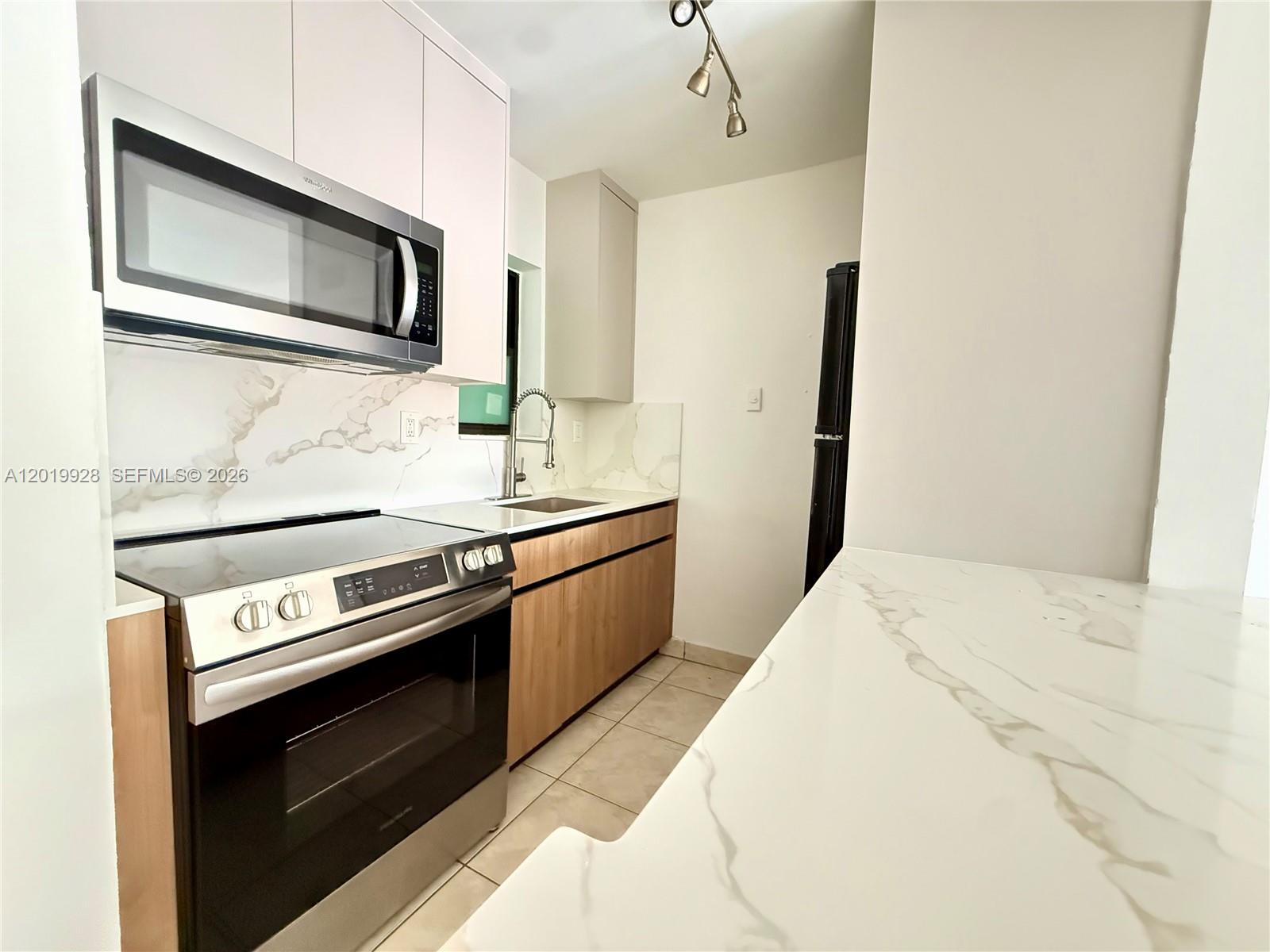 A modern kitchen features light wood cabinets, marble-patterned countertops, and stainless steel appliances — 1530 SW 2nd St # 304, Miami FL 33135, MIAMI, FL