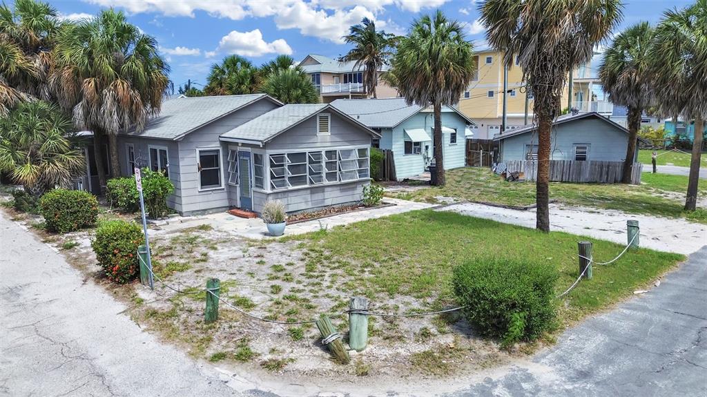 A gray cottage with a screened porch sits on a sandy lot with palm trees — 130 90TH AVENUE, TREASURE ISLAND, FL