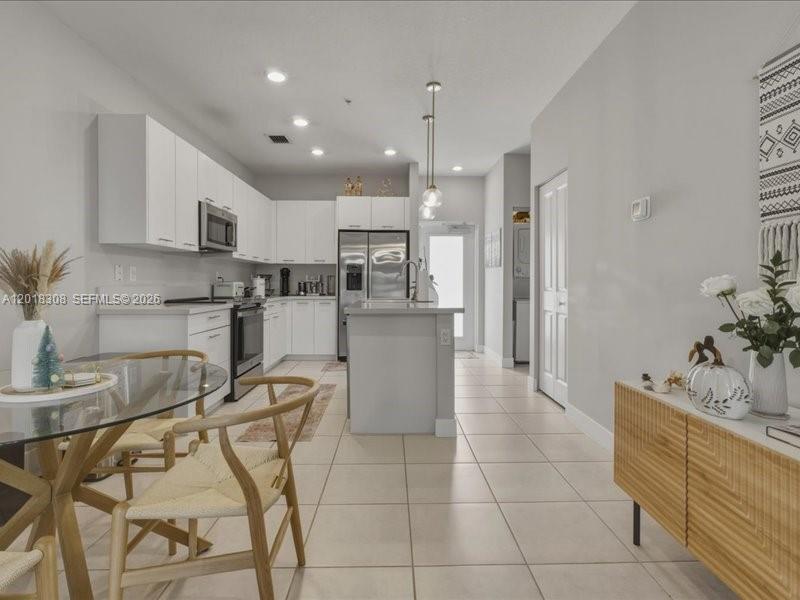 A modern kitchen features white cabinetry, stainless steel appliances, and a central island — 8201 NW 41st St # 205, Doral FL 33166, DORAL, FL