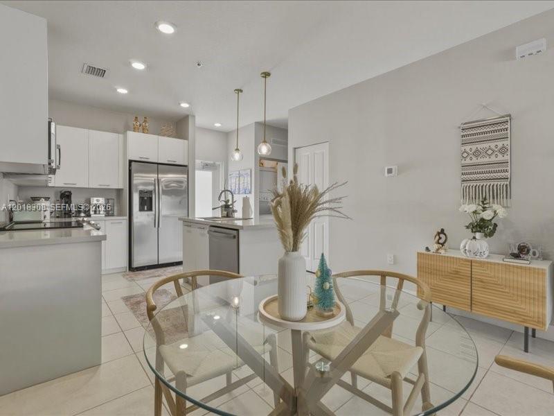 A modern kitchen with white cabinets and a glass dining table in the foreground — 8201 NW 41st St # 205, Doral FL 33166, DORAL, FL