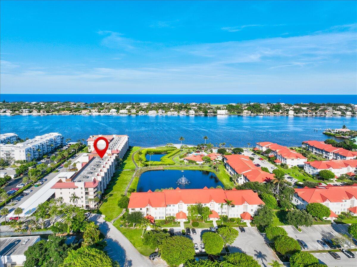 An aerial view shows a multi-story residential building with a red roof near a lake — 7030 Half Moon Circle # 515, Hypoluxo FL 33462, HYPOLUXO, FL