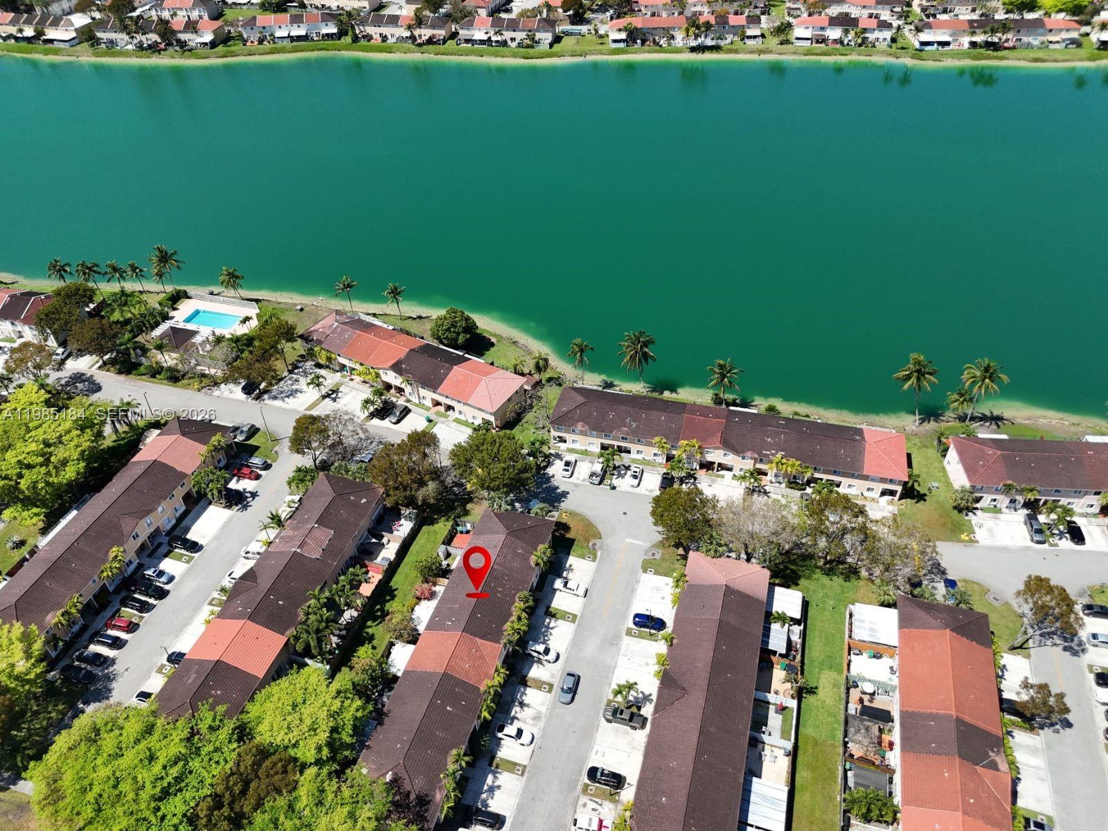 An aerial view shows a residential complex with townhouses situated along a large lake — 13926 SW 175th Ter, Miami FL 33177, MIAMI, FL