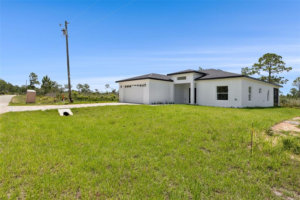 A newly constructed white single-story house with a garage sits on a grassy lot — 7435 CASILLA STREET, SEBRING, FL