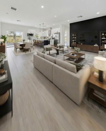 An open-concept living room and kitchen feature light wood flooring, a large sectional, and modern decor — 7435 CASILLA STREET, SEBRING, FL
