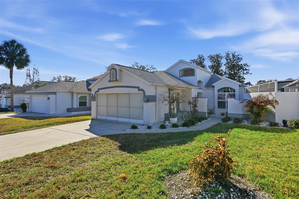 A single-story house with a white stucco exterior, a two-car garage, and a front lawn — 11008 CASA GRANDE, SPRING HILL, FL