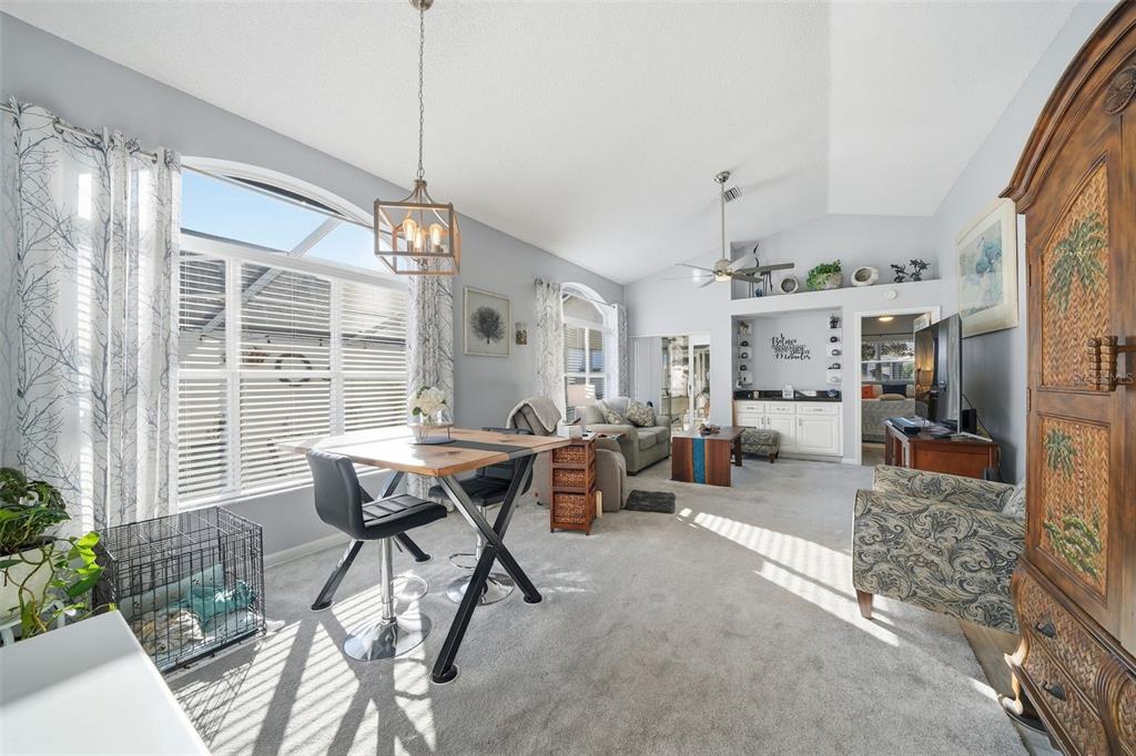 A living and dining area with carpeted floors, a vaulted ceiling, and a large window — 11008 CASA GRANDE, SPRING HILL, FL