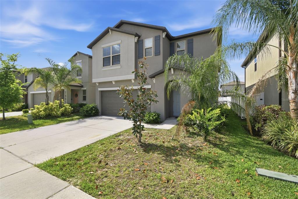 A two-story suburban house with a gray stucco exterior, a garage, and a front lawn — 7329 CANTERBURY BELLS COURT, TAMPA, FL