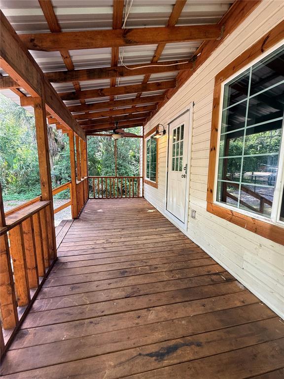 A covered wooden porch features a ceiling fan, railing, and a white door — 1229 NE 3RD  AVENUE, GAINESVILLE, FL