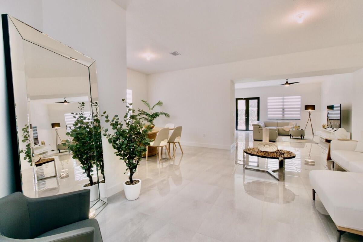 A bright, open-concept living and dining area features white tile floors and a large mirror — 17451 SW 41st Street, Miramar FL 33029, MIRAMAR, FL
