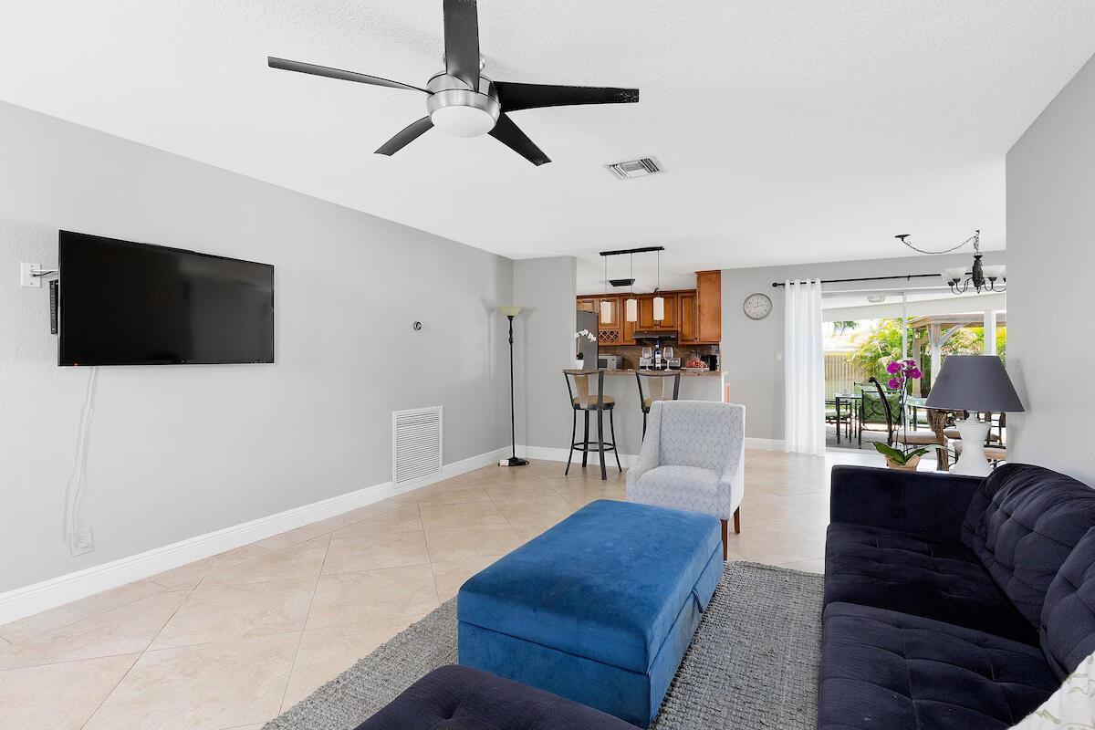 A living room features a blue sofa, a matching ottoman, and an open-concept kitchen — 4348 NW 2nd Terrace, Boca Raton FL 33431, BOCA RATON, FL