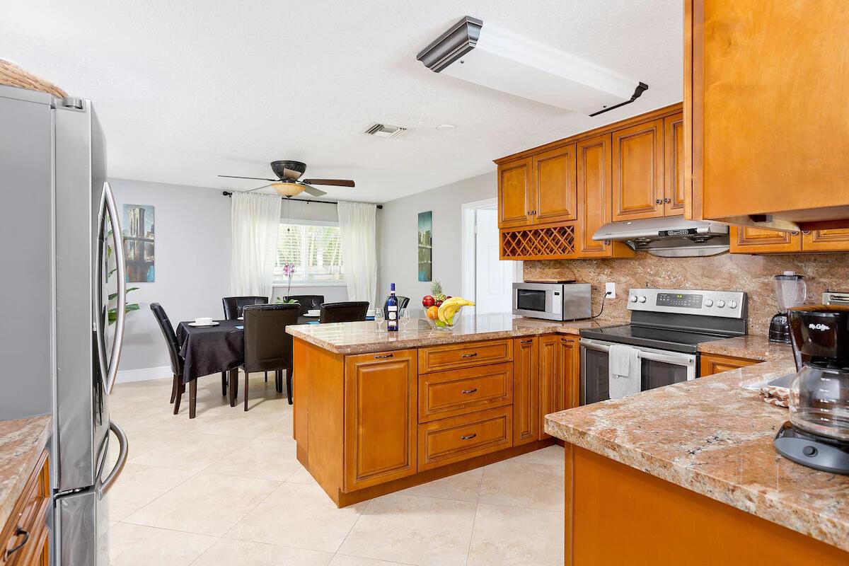 A kitchen with wood cabinets and granite countertops opens to a dining area — 4348 NW 2nd Terrace, Boca Raton FL 33431, BOCA RATON, FL