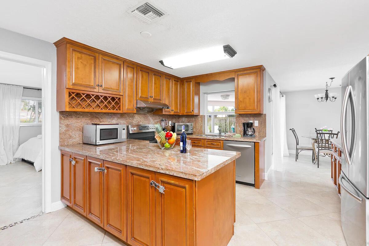 A kitchen features wood cabinets, granite countertops, stainless steel appliances, and a central island — 4348 NW 2nd Terrace, Boca Raton FL 33431, BOCA RATON, FL