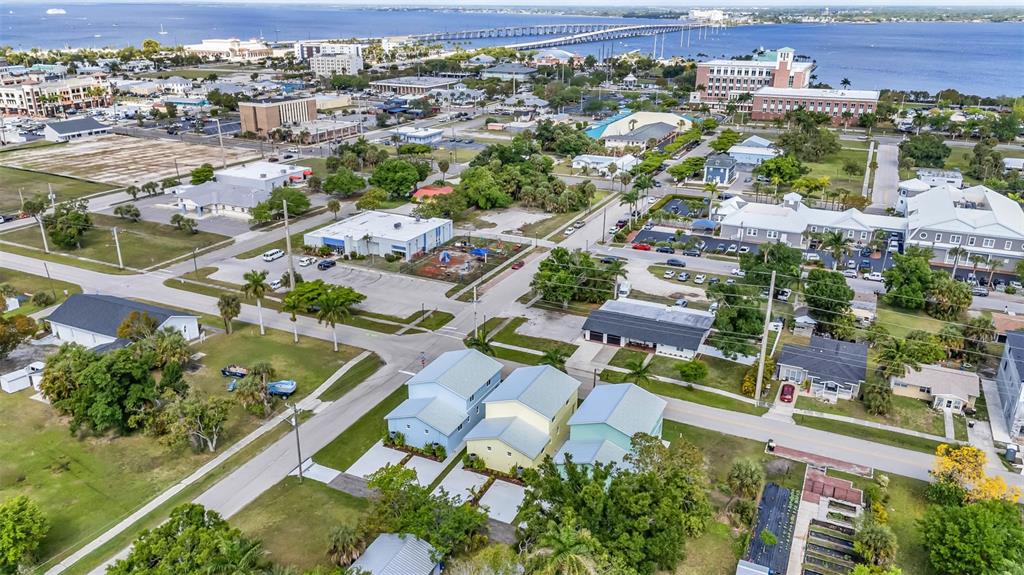 An aerial view shows three pastel-colored houses in a residential area near a large bay — 309 E VIRGINIA AVENUE, PUNTA GORDA, FL