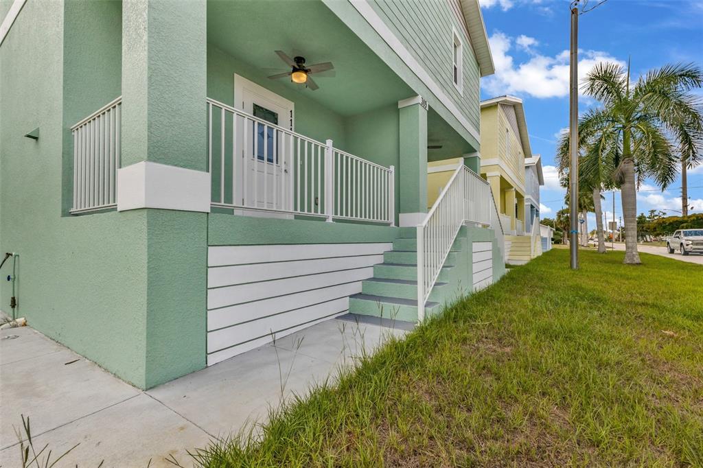 A light green elevated house features a front porch with white railings and stairs — 309 E VIRGINIA AVENUE, PUNTA GORDA, FL