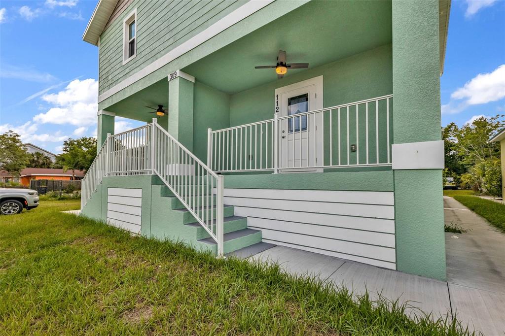 A light green elevated house features a front porch with white railings and stairs — 309 E VIRGINIA AVENUE, PUNTA GORDA, FL