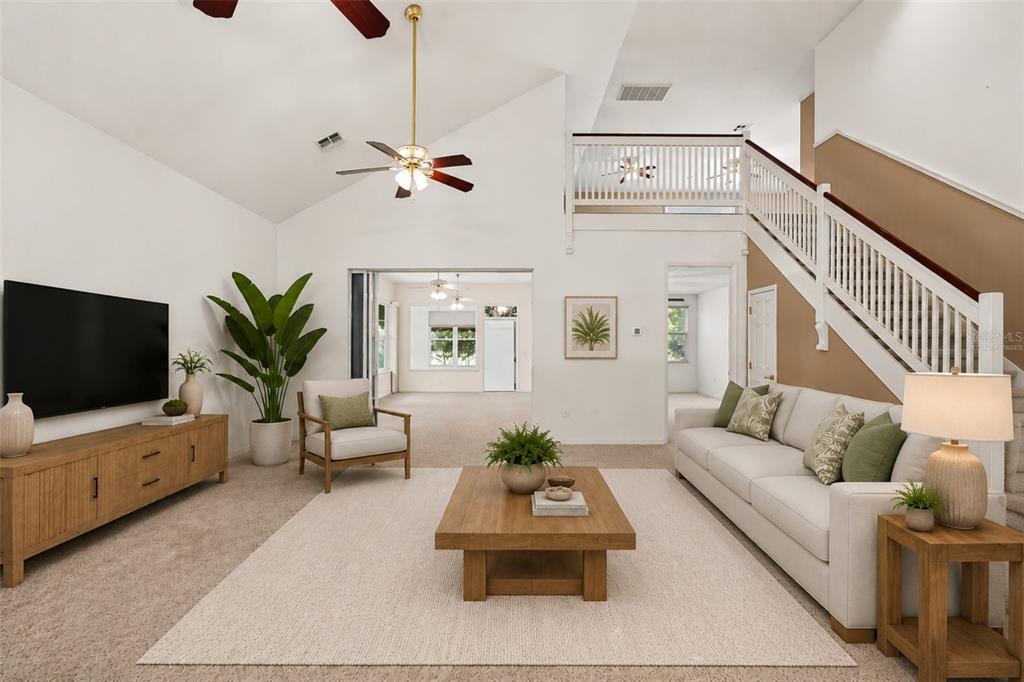 A living room features a vaulted ceiling, a staircase, and a neutral color palette — 1075 MOTORCOACH DRIVE, POLK CITY, FL