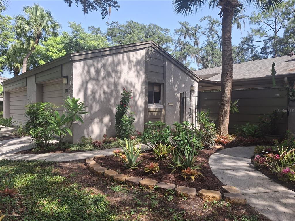 A single-story house exterior features a garage, a landscaped garden bed, and a concrete walkway — 602 WOODRIDGE DRIVE, CASSELBERRY, FL