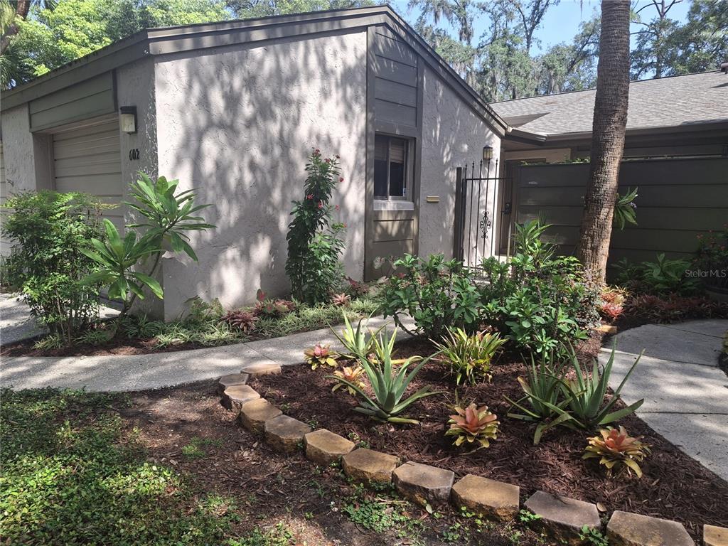 A single-story home exterior features a garage, a landscaped front garden, and a gated entrance — 602 WOODRIDGE DRIVE, CASSELBERRY, FL