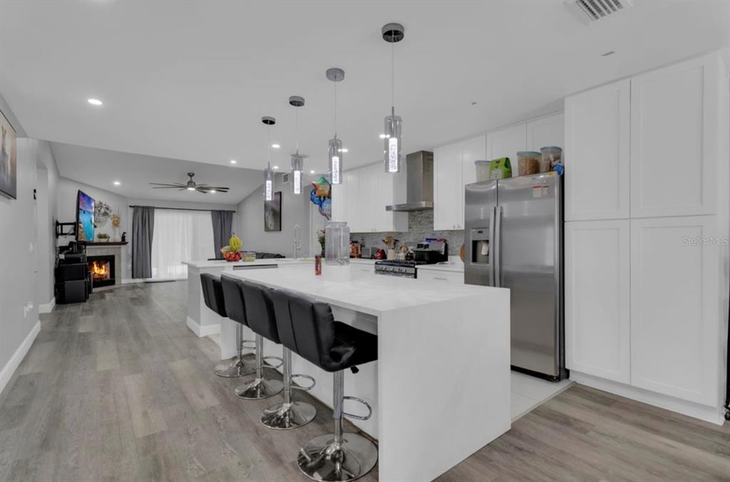 A modern white kitchen features a large island, stainless steel appliances, and recessed lighting — 4849 EDEN VIEW COURT, ORLANDO, FL