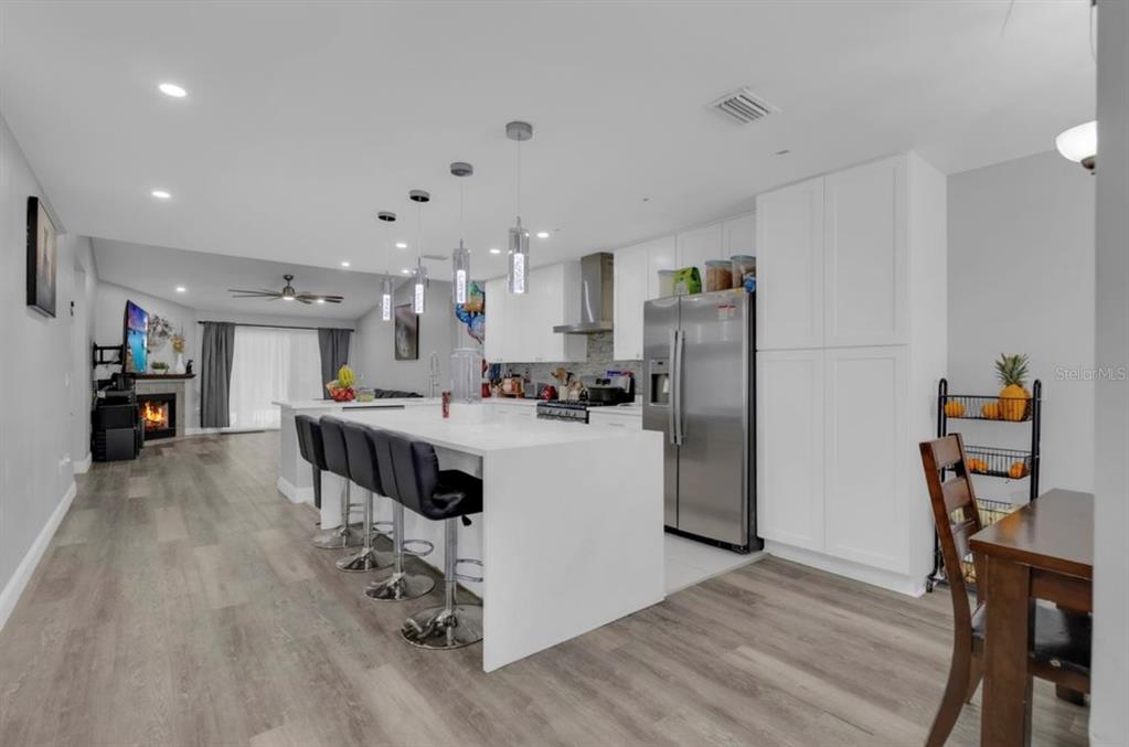 A kitchen features white cabinets, a stainless steel stove, a range hood, and a refrigerator — 4849 EDEN VIEW COURT, ORLANDO, FL