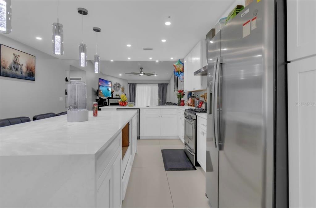 A kitchen island with a stainless steel sink overlooks a living room with a fireplace — 4849 EDEN VIEW COURT, ORLANDO, FL