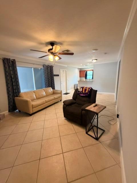 A living room features a beige sofa, a dark recliner, and light-colored tile flooring — 1983 Juno Road, North Palm Beach FL 33408, NORTH PALM BEACH, FL
