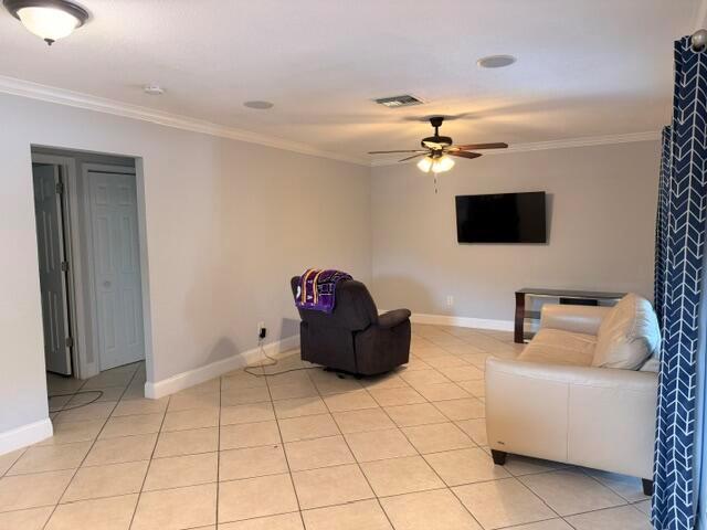 A living room features light-colored tile flooring, a ceiling fan, a sofa, and a recliner — 1983 Juno Road, North Palm Beach FL 33408, NORTH PALM BEACH, FL
