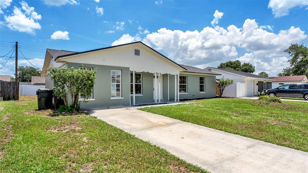A single-story house with a green brick exterior and a concrete driveway under a blue sky — 1726 CORDOVA CIRCLE W, LAKELAND, FL