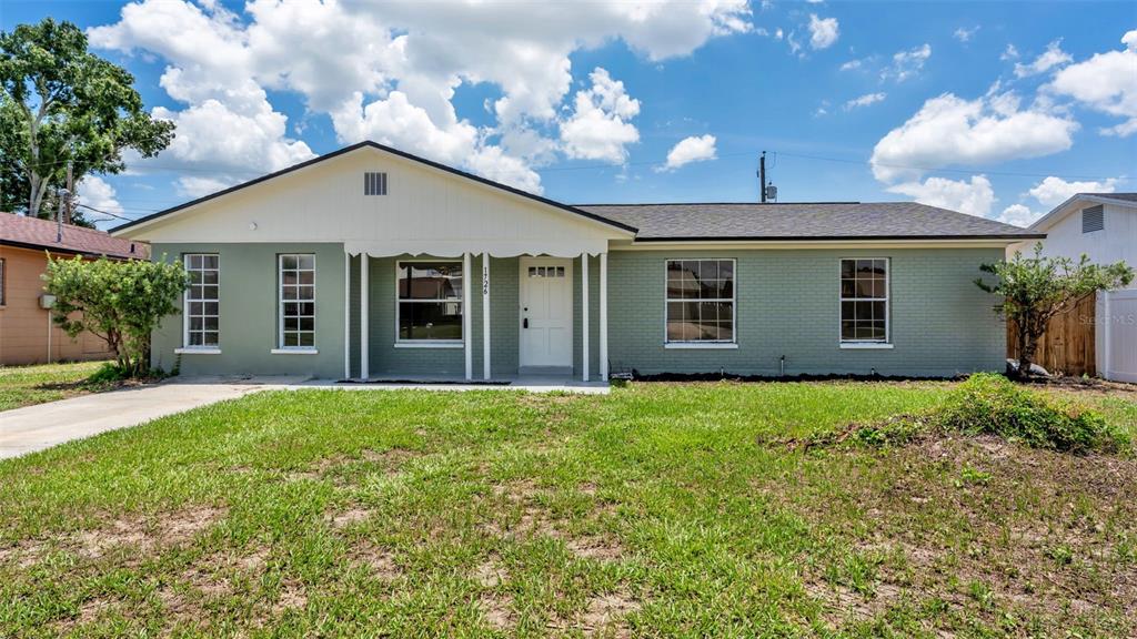 A single-story house with a green brick exterior, white trim, and a front porch — 1726 CORDOVA CIRCLE W, LAKELAND, FL