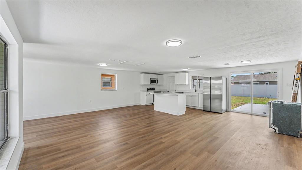 A bright, open-concept kitchen and living area with white cabinets and wood-look flooring — 1726 CORDOVA CIRCLE W, LAKELAND, FL
