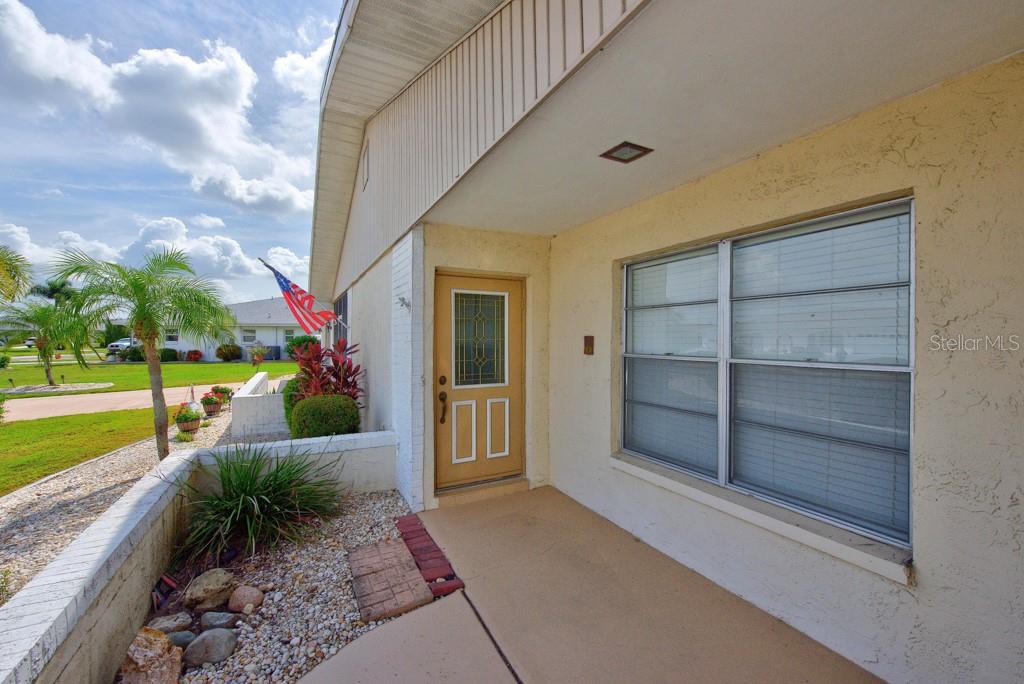 A tan front door and a large window are visible on the covered porch — 106 SILVERBELL COURT, SUN CITY CENTER, FL