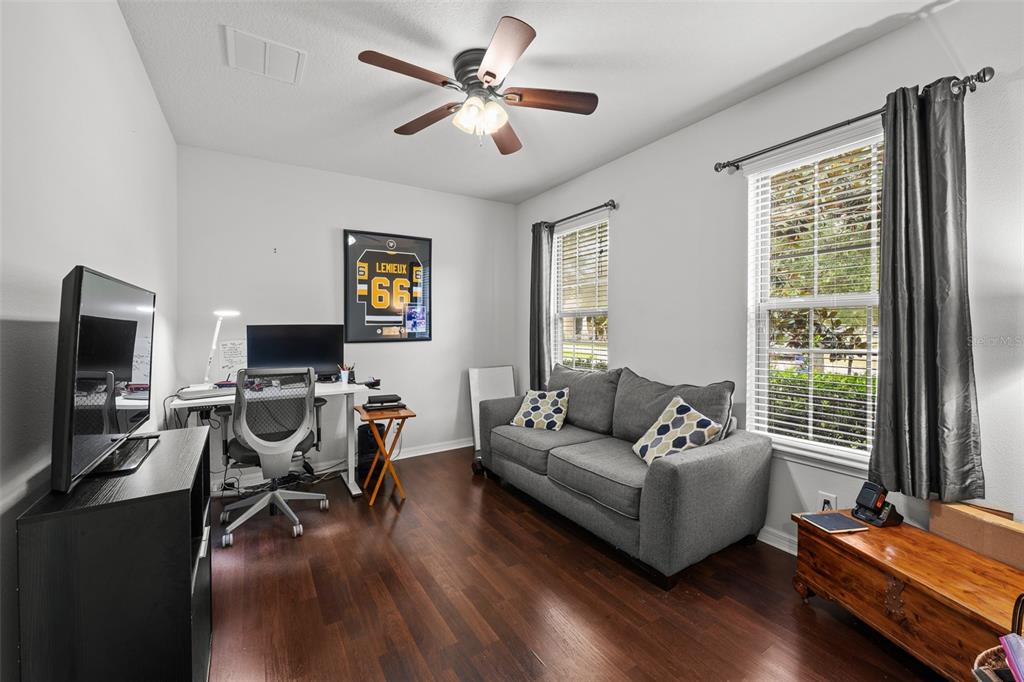 A home office features dark wood flooring, a gray sofa, a desk, and a ceiling fan — 2212 LANDSIDE DRIVE, VALRICO, FL