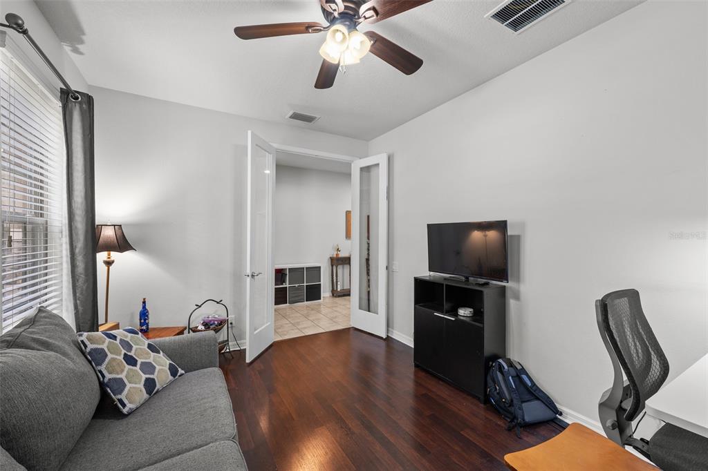 A home office features a gray sofa, a television on a stand, and French doors — 2212 LANDSIDE DRIVE, VALRICO, FL