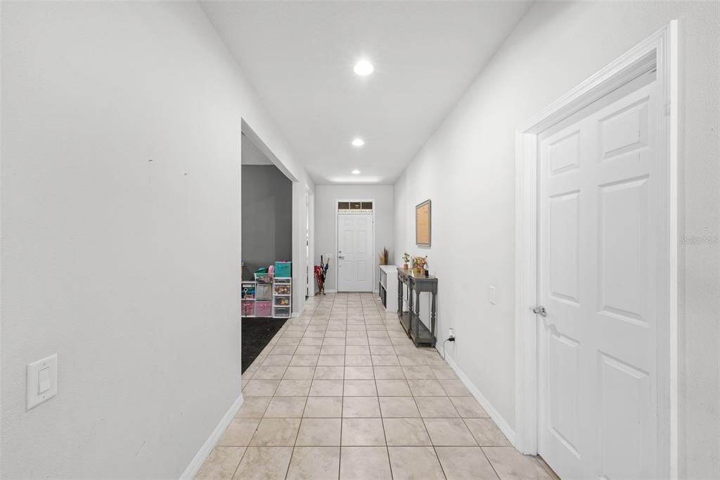 A tiled hallway leads to a white front door with recessed lighting and white walls — 2212 LANDSIDE DRIVE, VALRICO, FL