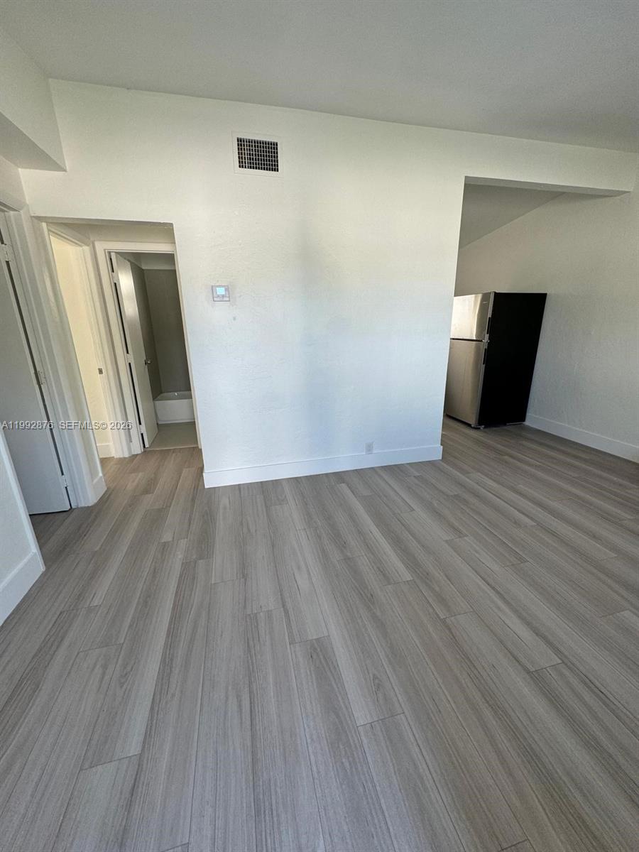 A room with light wood-look flooring leads to a bathroom and a kitchen area — 2005 Ali Baba Ave, Opa-Locka FL 33054, OPA-LOCKA, FL
