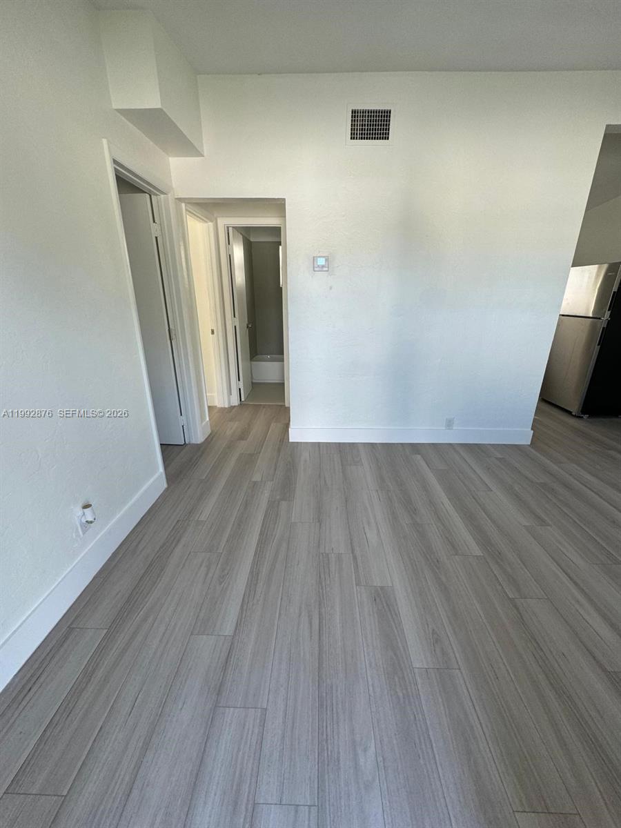 A room with light-colored wood-look flooring and doorways leading to a bathroom and kitchen — 2005 Ali Baba Ave, Opa-Locka FL 33054, OPA-LOCKA, FL