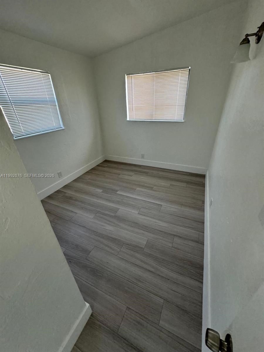 This room features white walls, light wood-look flooring, and two windows with blinds — 2005 Ali Baba Ave, Opa-Locka FL 33054, OPA-LOCKA, FL