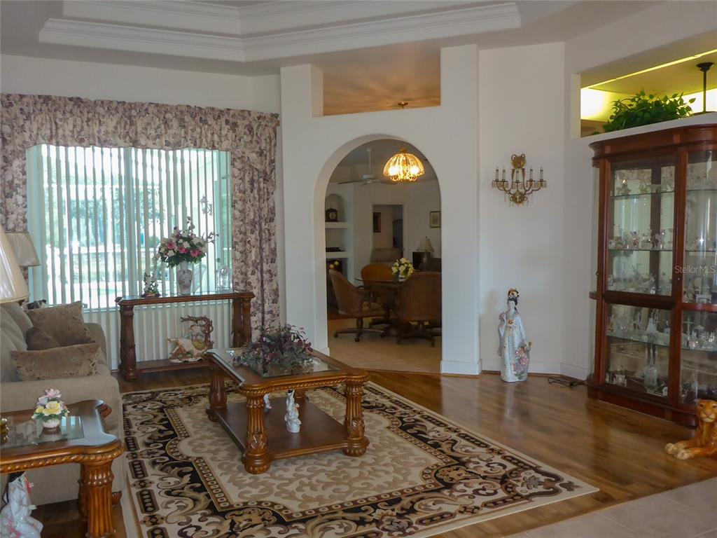 A living room features hardwood floors, an arched doorway, and a large wooden display cabinet — 12271 CENTRALIA RD, WEEKI WACHEE, FL