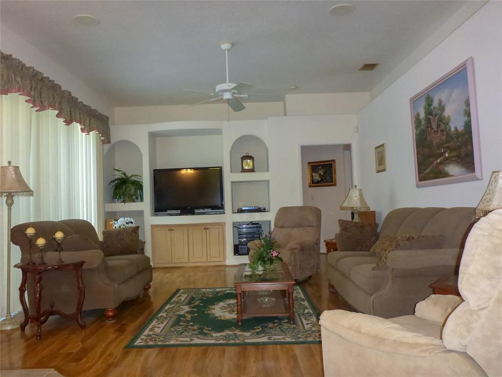 A living room features a built-in media center, hardwood floors, and a green area rug — 12271 CENTRALIA RD, WEEKI WACHEE, FL